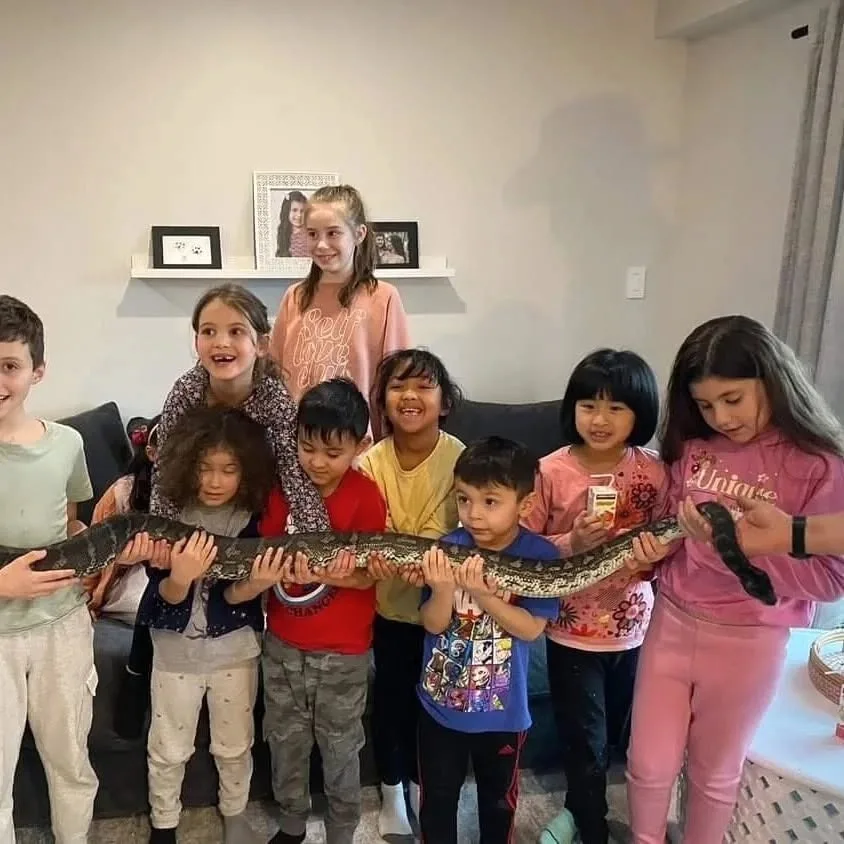 Birthday party group holding a large snake together