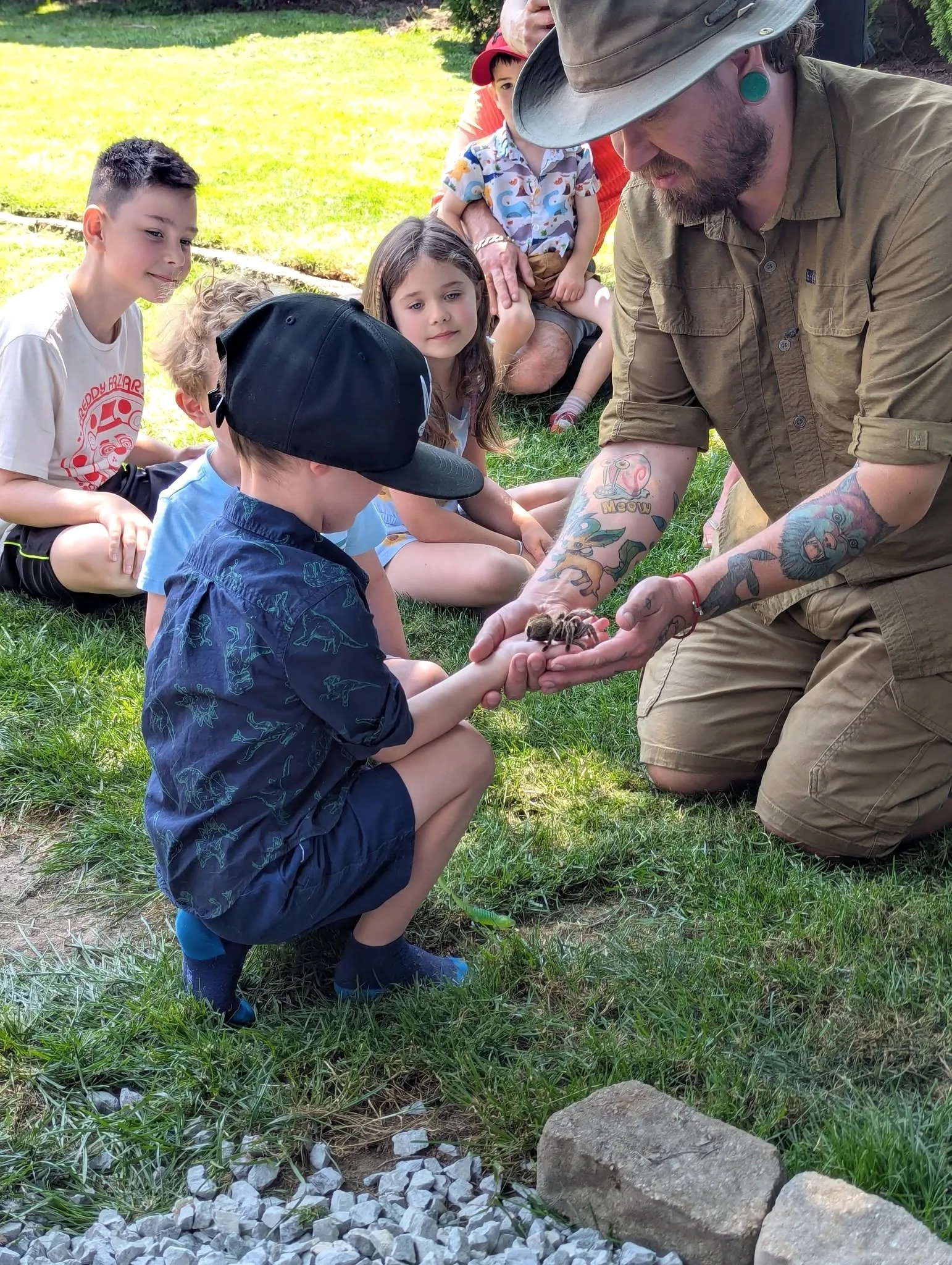 A presenter guiding a child holding a snake at a birthday party