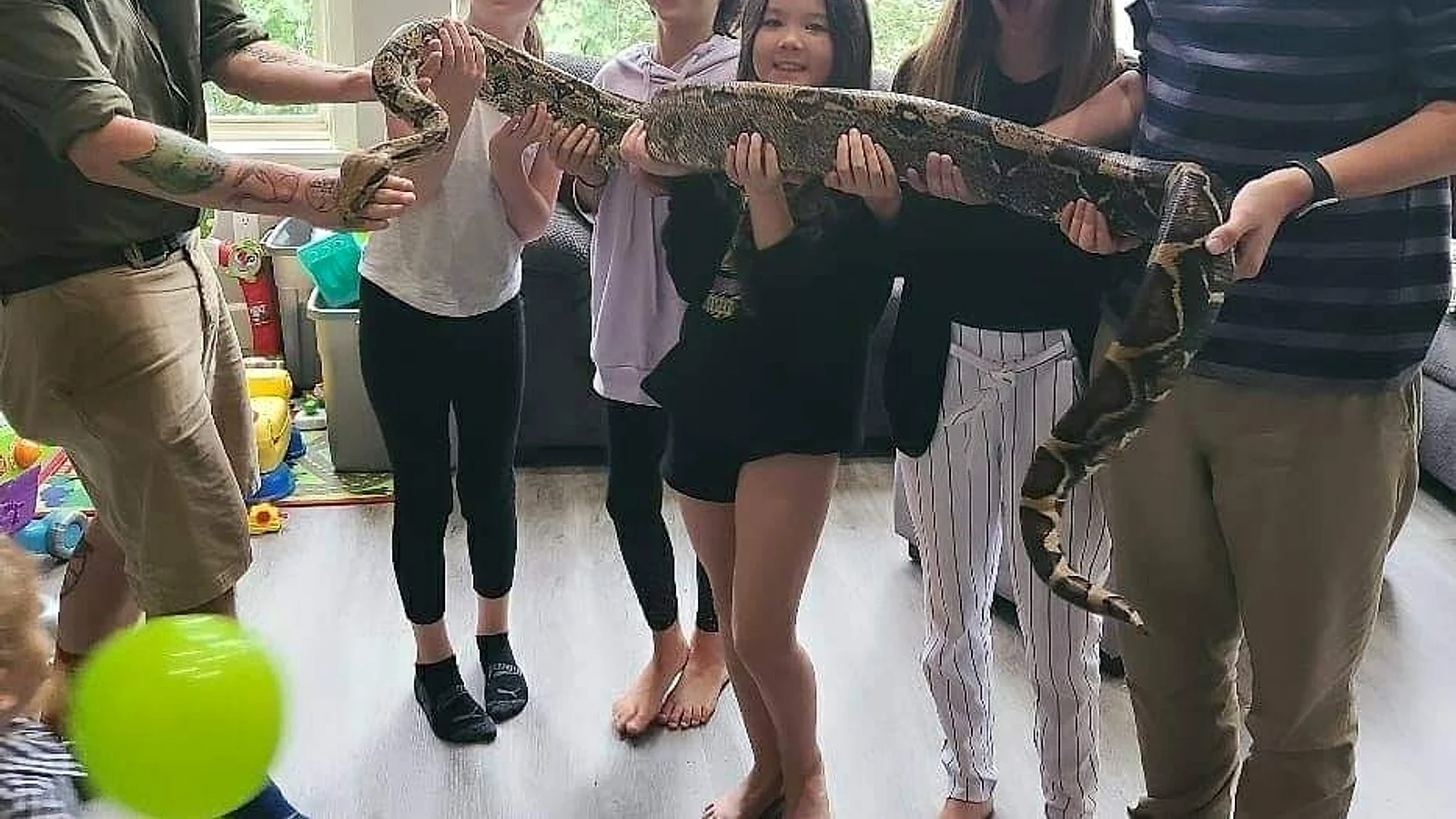 Children meeting and supporting a large snake during an educational birthday presentation.