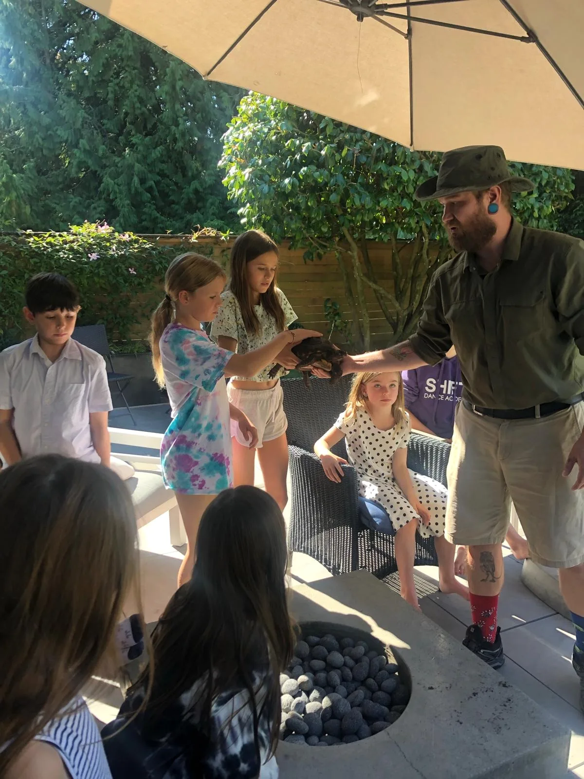 Kevin leading a shaded outdoor group presentation with a tortoise